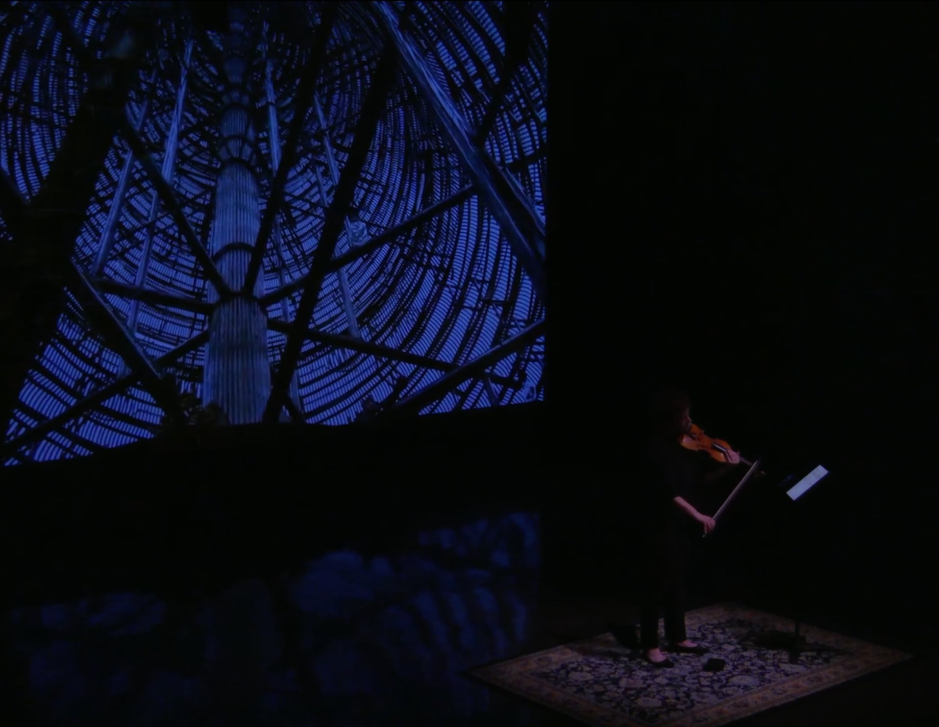 Wide view of Sarah Saviet performing with the video projection for Travelogue: Surat → Hat Yai, sul G.